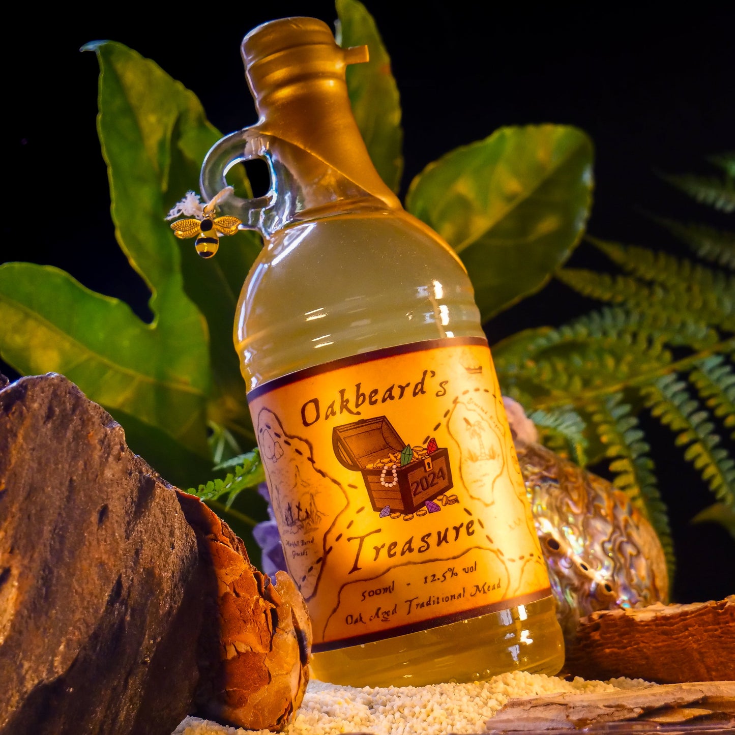 A bottle of Oakbeard's Treasure sat in a beach amongst rocks, vegetation, and sand. Credit to Nerdventure
