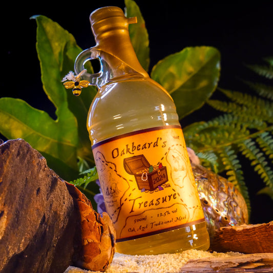 A bottle of Oakbeard's Treasure sat in a beach amongst rocks, vegetation, and sand. Credit to Nerdventure