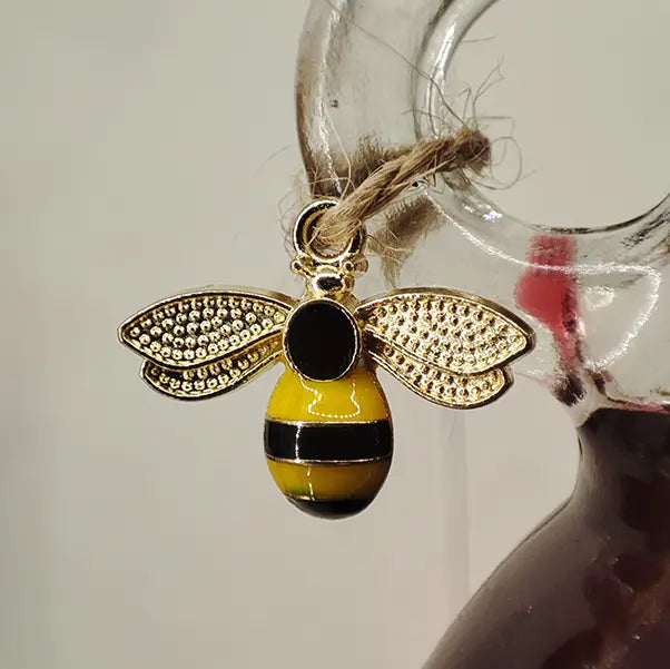 A close up of the included bee charm, attached to the bottle handle with twine.