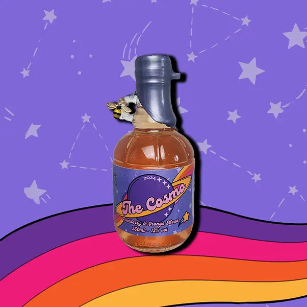 A mini 250ml bottle of The Cosmo Mead. A wax dipped bottle with a label. A small bee charm hangs from the finger handle on the bottle.